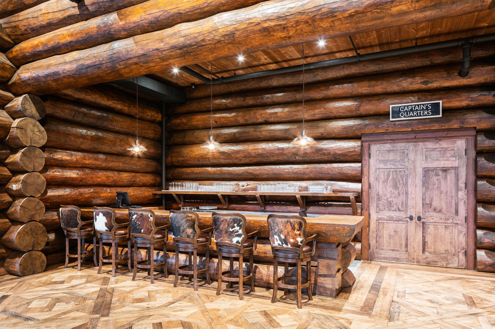 The long wood bar with cowhide stools beside the Captain's Quarters doorway