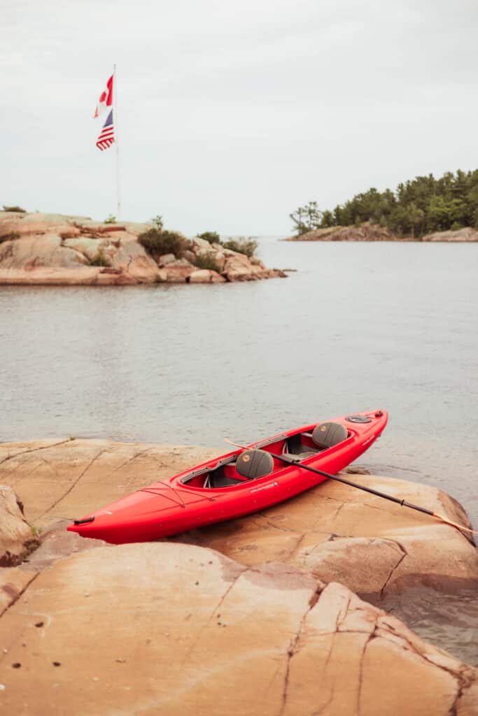 Red kayak resting on smooth pink granite
