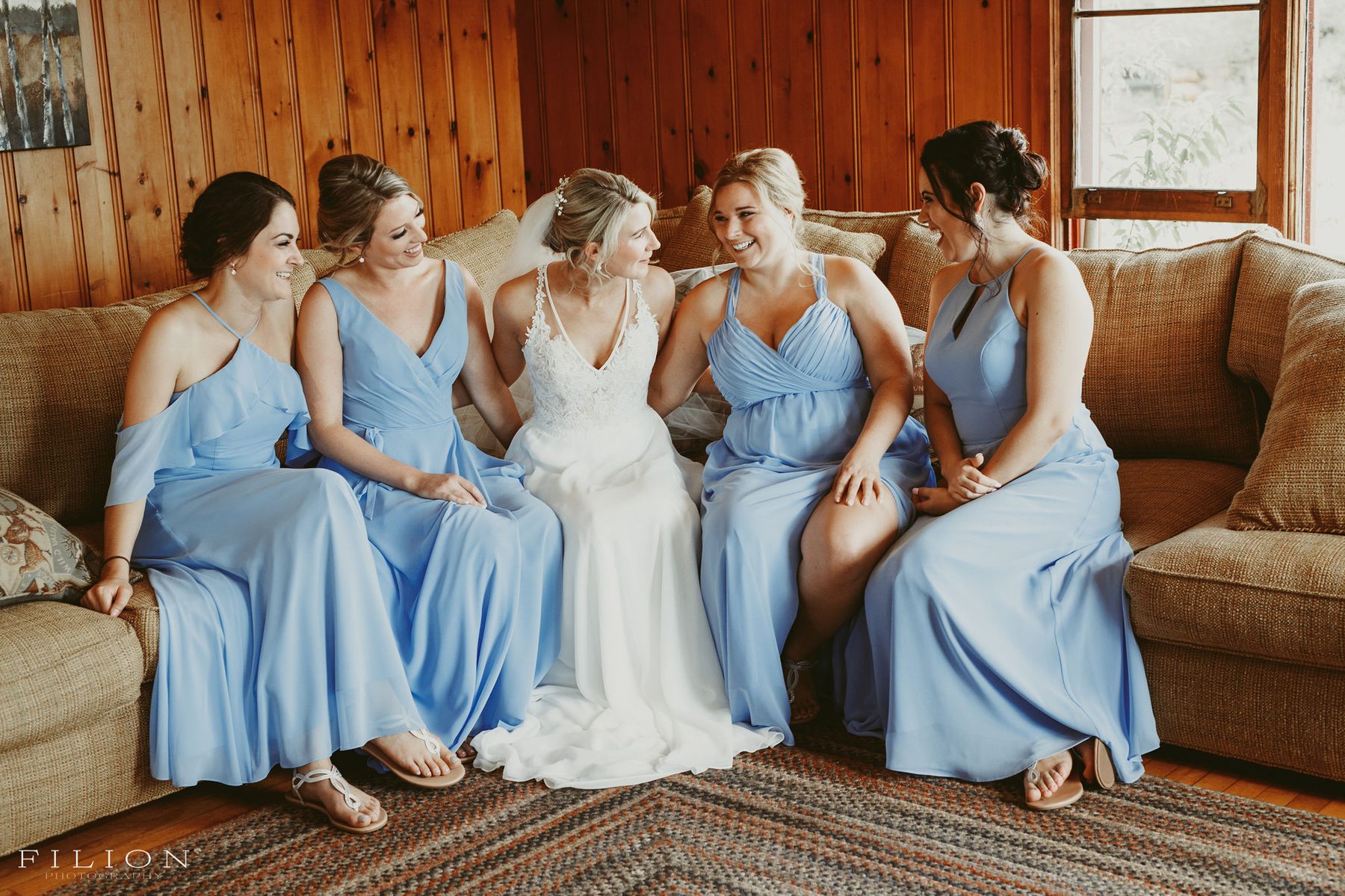 Bride laughing with bridesmaids in a pine-panelled cabin