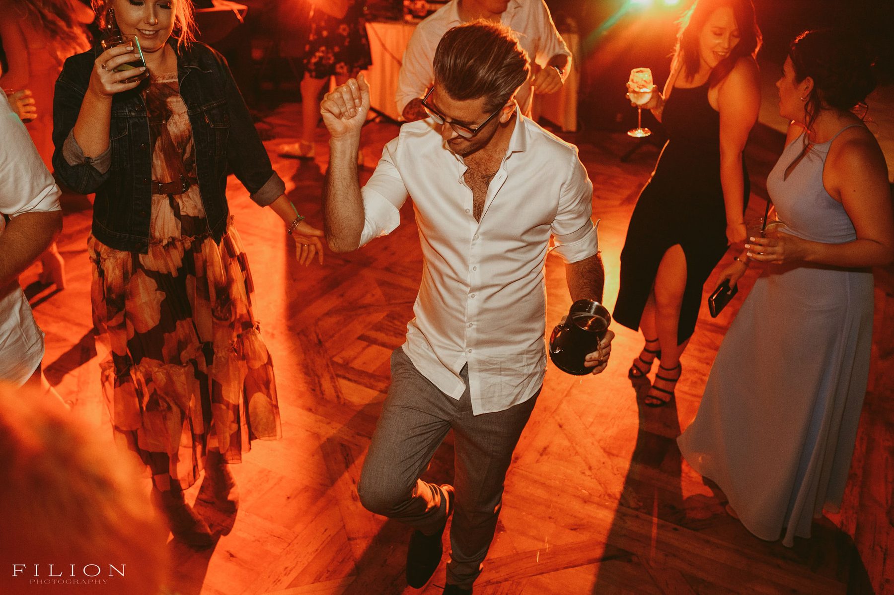Guests dancing under warm light on the reception floor